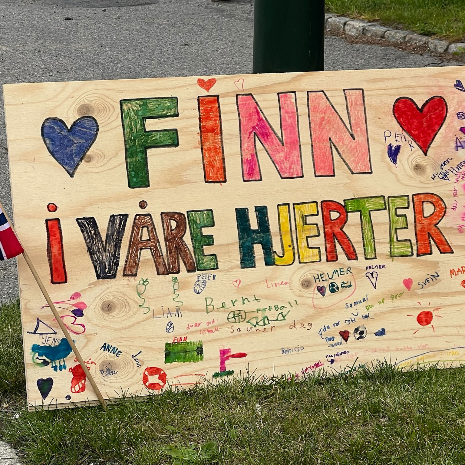 Treplakat med teksten Finn i våre hjerter ved siden av veien